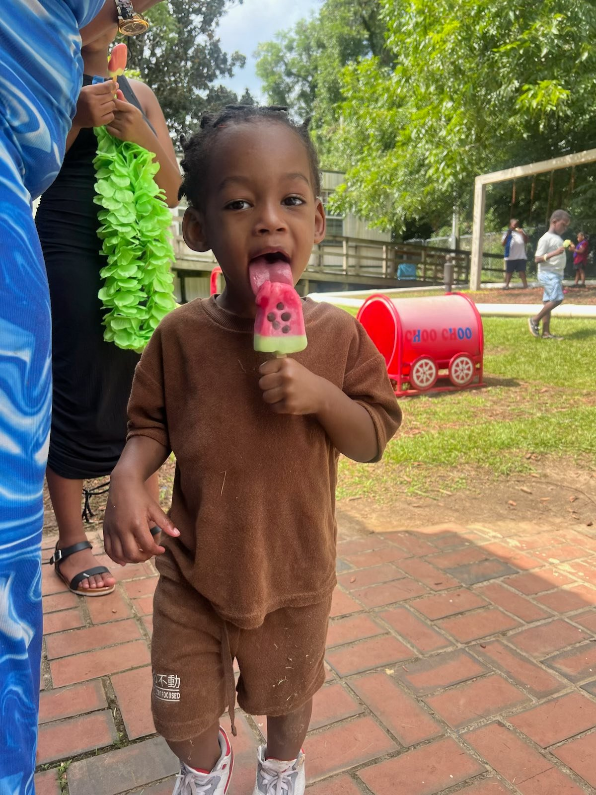Toddler enjoying a watermelon popsicle on the playground